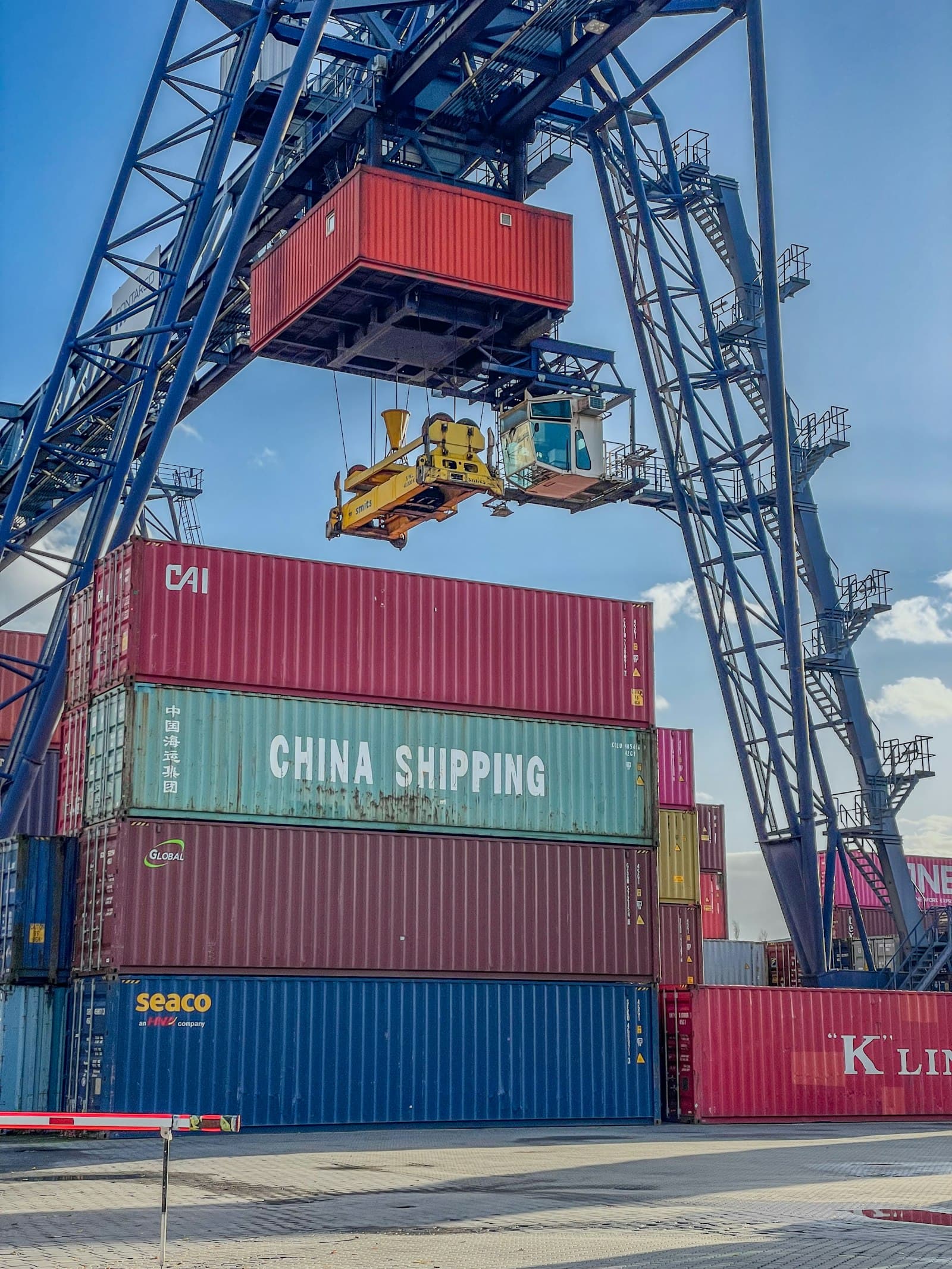 A crane lifting a shipping container onto a truck at a freight terminal